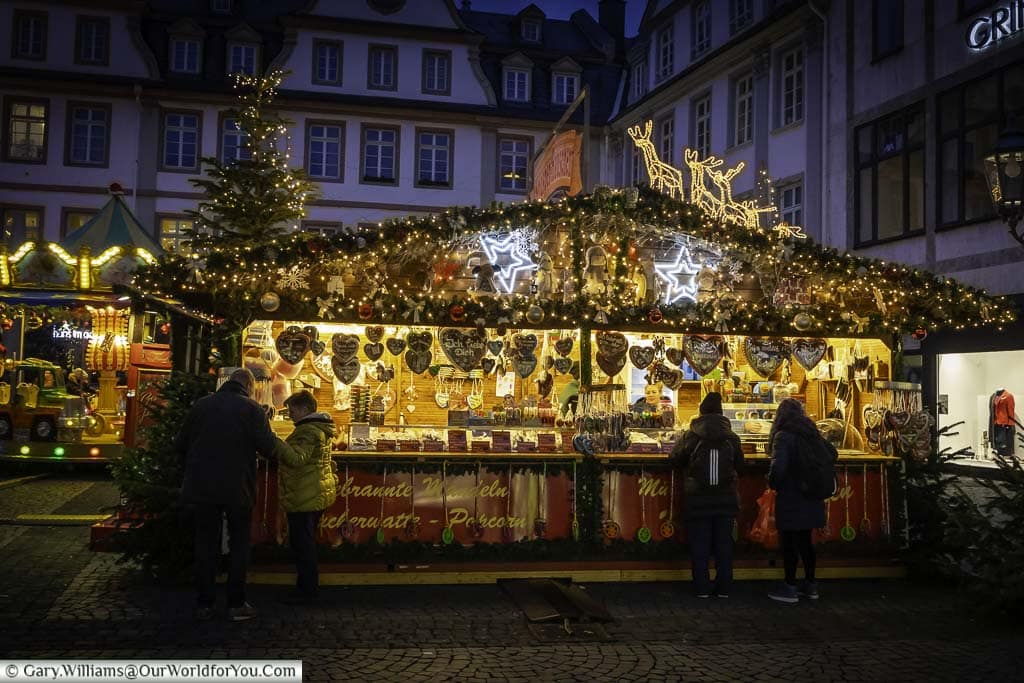 people choose their gingerbread from an illuminated and decorated stall in koblenz's am plan christmas market at dusk