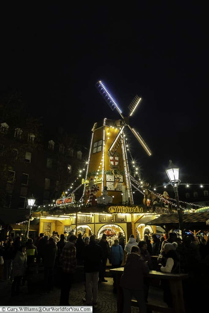 crowds gathering under the glühwein windmill in koblenz's münzplatz christmas market at night