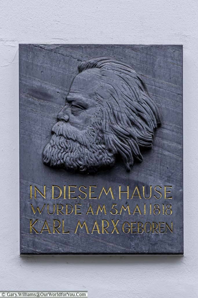 a slate plaque with an embossed profile head shot of an older karl marx as fitted to the outside of his former home, now musuem, in trier, germany