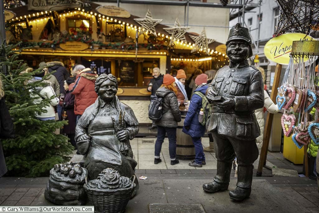A couple of comic bronze statues of policeman otto and market woman ringelstein in front of the christmas markets in münzplatz, koblenz