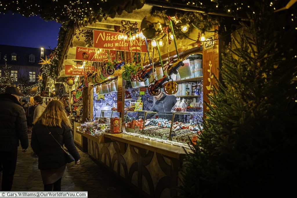 A decorated nut seller stall at the edge of trier's cathedral christmas market at dusk
