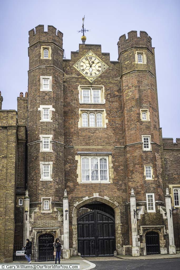 The gatehouse entrance to St James' palace in London, with its large clock face between two brick built towers