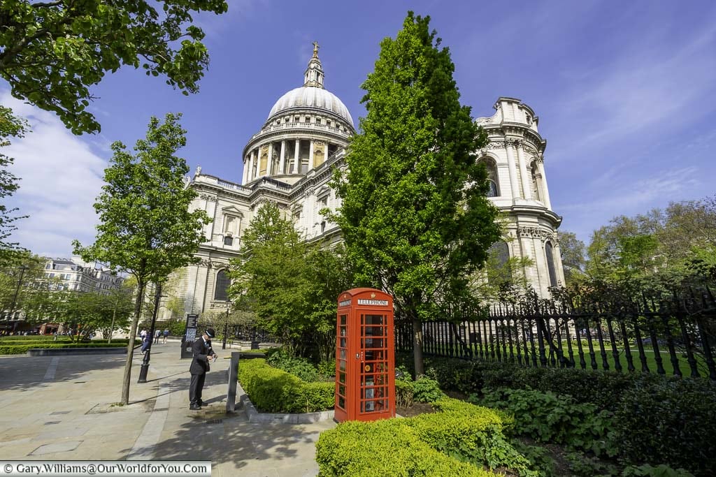 A red telephone box with saint paul's cathedral in the background in the city of london