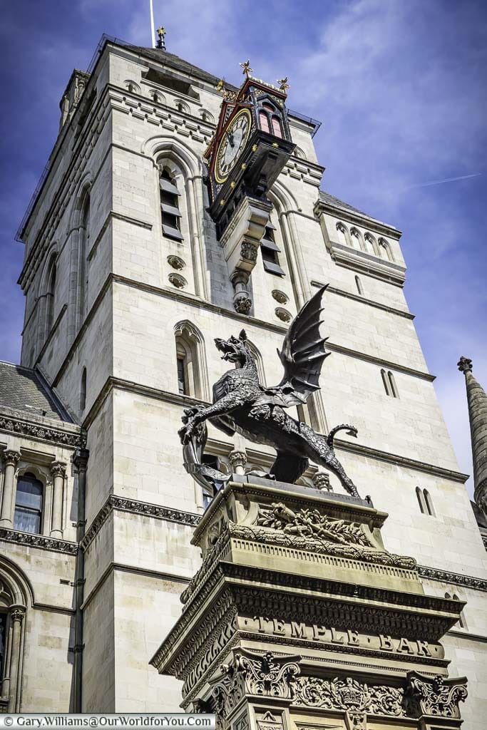 The ornate iron statue of a dragon on the temple bar plinth in front of the corner of the royal courts of justice on the strand