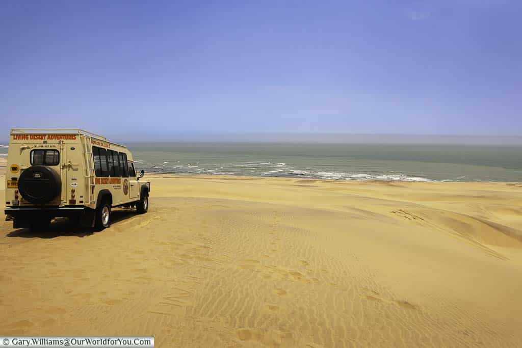 The little 5 desert tour safari land rover parked on a sand dune overlooking the sea at walvis bay, swakopmund in namibia