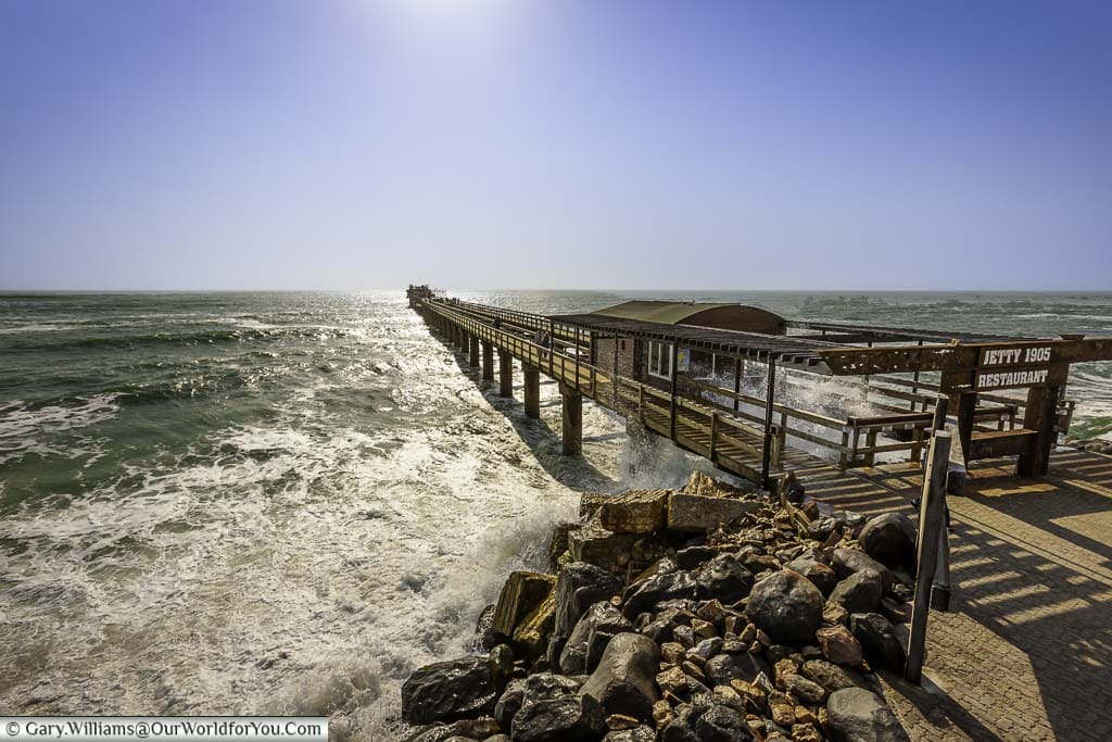 The old colonial pier heading out a long way into the atlantic ocean at swakopmund in namibia as waves crash against the shoreline