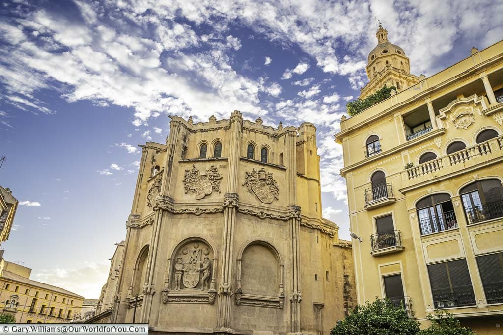 A photo of the vélez chapel, a historic building with a tall bell tower, located next to the murcia cathedral in murcia, spain. The sky is blue with some clouds.