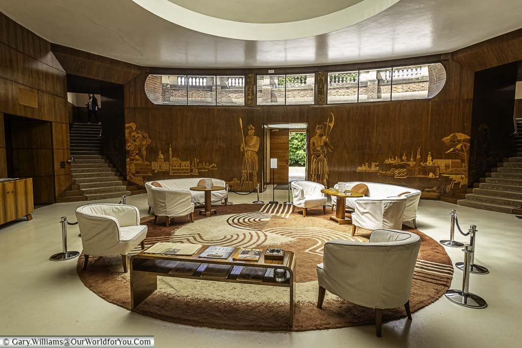 The opulent reception area of Eltham Palace in south east London with wood panels engraved with classical scenes. The whole area is an art deco masterpiece.