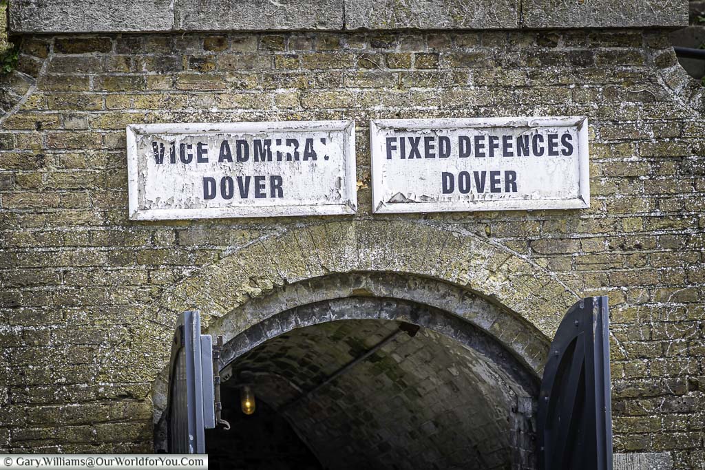 Two wooden signs over a gated entrance leading to the world war two tunnels at dover castle in kent