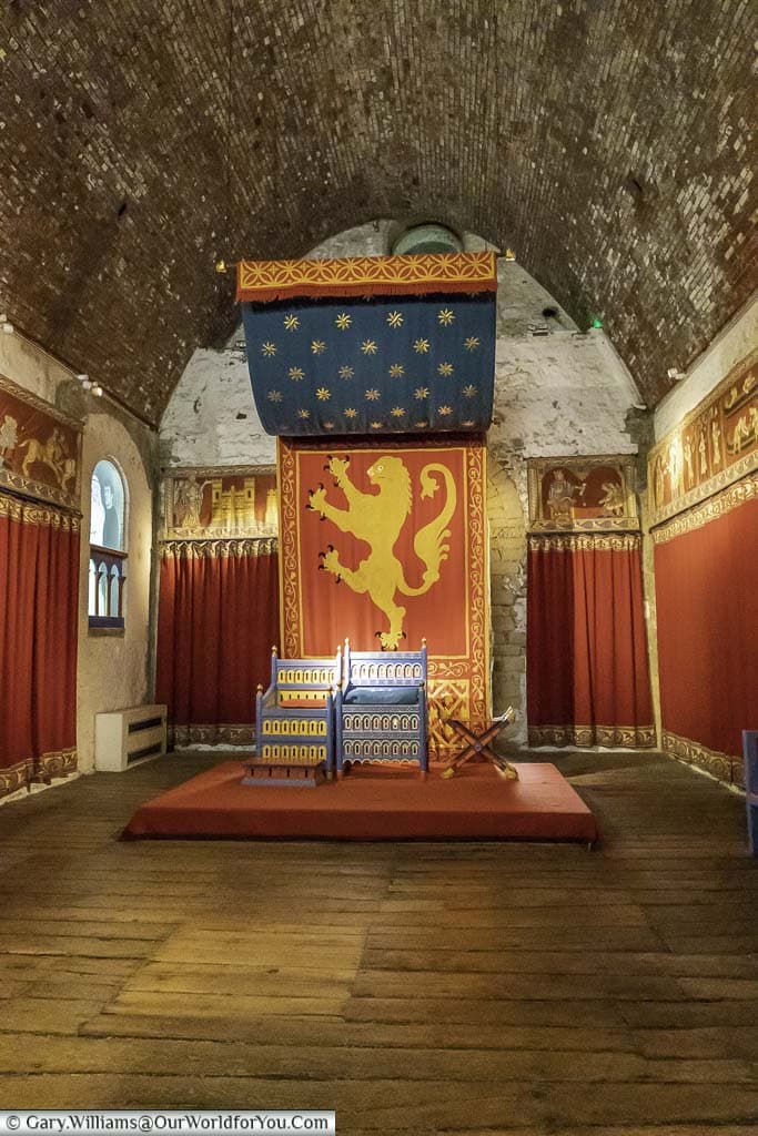 A basic throne, alongside a matching seat, in front of norman drapes in the english heritage dover castle