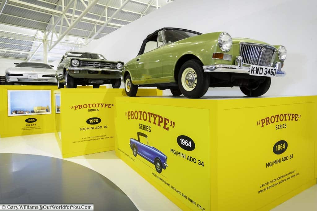 Full size prototype British cars displayed on scaled-up toy boxes