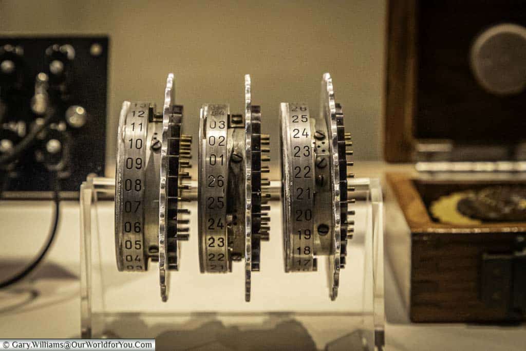 Three of the encryptions wheels, isolated from an Enigma machine, mounted on a perspex display stand in a display cabinet at Bletchley Park