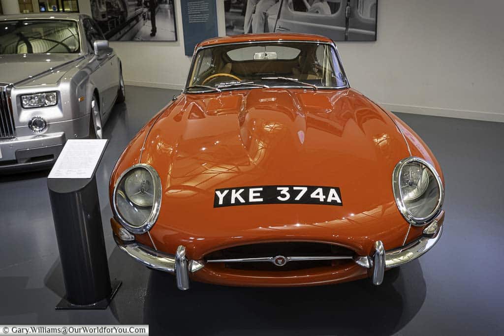 A front view of a bright red 1960's E-Type Jaguar in the entrance lobby of the British Motor Museum