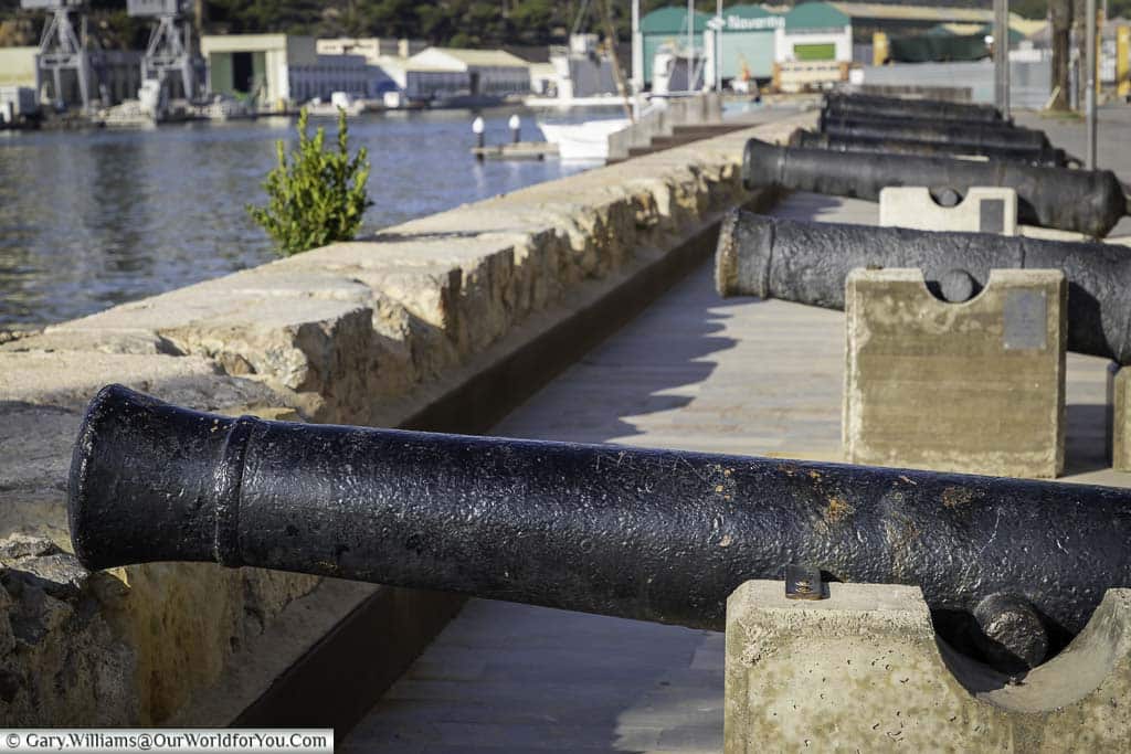 A row of iron canons lined up on cartegena's harbour edge in front of the cartagena naval museum